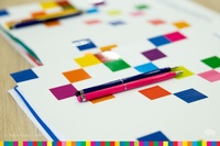 Na teczce z kolorowymi pikselami leżą dwa długopisy